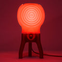 The glowing Visitor table lamp in Cherry-Dip illuminates a dark room.