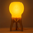 The glowing Visitor table lamp in Lemon-Dip illuminates a dark room.